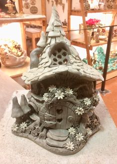 a statue of a gnome's house with flowers on the ground in front of it