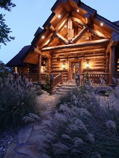 a log cabin with lights on the porch and steps leading up to the front door