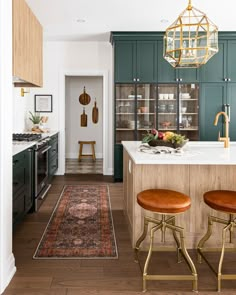 a kitchen with green cabinets and wooden stools