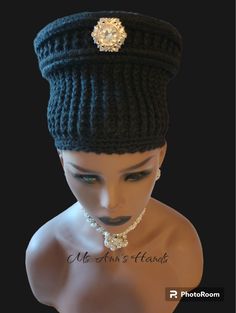 a mannequin head wearing a black hat with a jeweled brooch on it