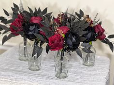 three glass vases with flowers in them on a white tablecloth covered table cloth