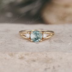 a close up of a ring with a blue stone in the middle and three diamonds on it