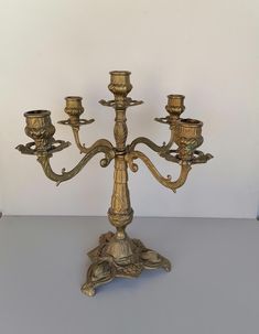 a gold colored candelabra with five candles on it's stand,