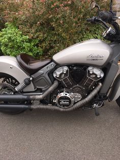 a silver motorcycle parked in front of some bushes