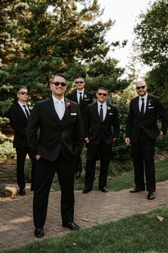 a group of men in suits and sunglasses standing next to each other on a sidewalk