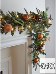 a christmas garland with pine cones and ornaments hanging from it's side on a fireplace mantel