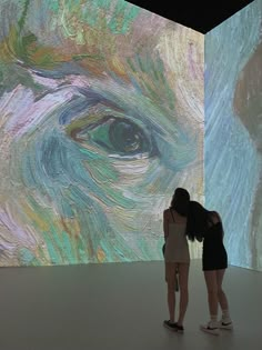 two girls are standing in front of a large painting that is being projected on the wall