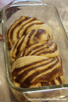 some food is in a glass dish on a tableclothed cloth and it looks like cinnamon rolls