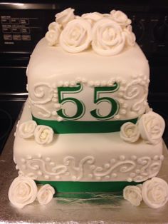 a white cake with green ribbon and flowers on it's side sitting on top of a counter