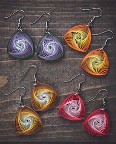 six pairs of earrings with different colors and shapes on wooden background, close up photo