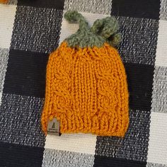 an orange knitted hat sitting on top of a checkered table cloth