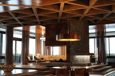 a living room filled with lots of furniture next to tall windows and wooden beams on the ceiling