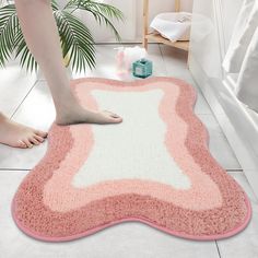 a person is standing on the bathroom floor next to a pink and white bath mat