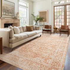 a living room filled with furniture and a large rug on top of a hard wood floor