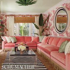 a living room filled with pink couches and pillows on top of a striped rug