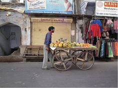 a man standing next to a cart filled with fruit