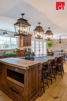 a large kitchen with wooden floors and lots of lights hanging from the ceiling over the island