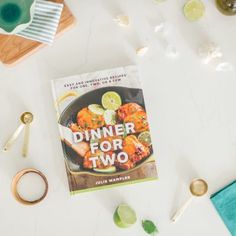 a cookbook sitting on top of a table next to other food and utensils