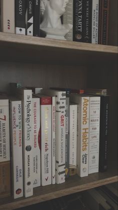 a book shelf filled with lots of books on top of wooden shelves next to a white busturine