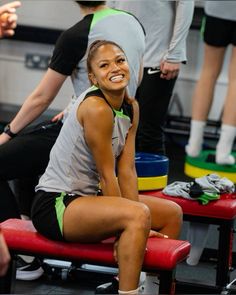 a smiling woman sitting on a bench in a gym