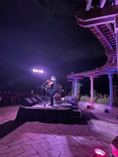 a man standing on top of a stage next to a microphone in front of a crowd