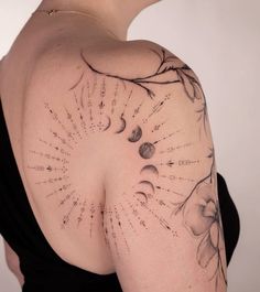 the back of a woman's shoulder with sun and moon tattoos on her arm