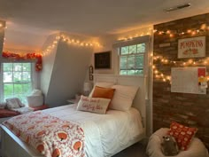 a bedroom decorated for fall with lights strung from the ceiling and pillows on the bed