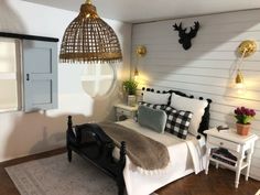 a bed room with a neatly made bed next to a window and a deer head mounted on the wall