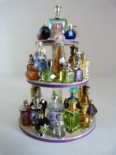 a three tiered display with perfume bottles on it's sides and glass ornaments in the middle