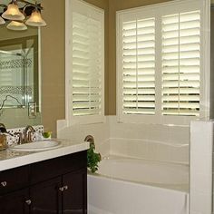 a bath room with a sink a mirror and a bath tub sitting next to a window