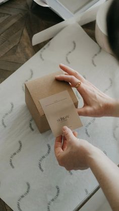 a person holding a piece of paper in front of a box on top of a table