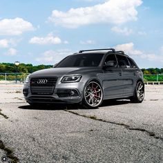 an audi suv parked in a parking lot with sky and clouds behind the cars door