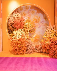 an arrangement of flowers on display in front of a colorful wall and carpeted floor