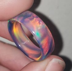 OPAREX synthetic opal is more durable and cost effective than your average opal, ensuring you will have your ring for years to come! The color shifts depending on the angle it is viewed, creating a rainbow of colors. The material is semi transparent, giving it an almost glowing effect. It is inspired by Dragon's Fire, displaying all the colors of a flame at it's hottest point. 8 mm wide This synthetic opal ring comes in a size 8 1/2 and was turned on a lathe. It is then sanded from 60 grit all t Multicolor Opal Round Ring, Multicolor Opal Ring Gift, Iridescent Opal Ring As A Gift, Iridescent Opal Ring Gift, Iridescent Opal Ring Perfect For Gifts, Multicolor Opal Ring, Unique Iridescent Round Opal Ring, Iridescent Opal Ring With Unique Style, Opal Band