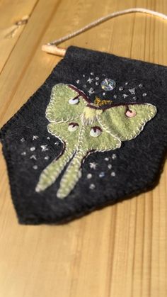 a small black bag with an image of a green butterfly on it's back