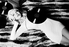 a black and white photo of a woman laying on top of a zebra print rug