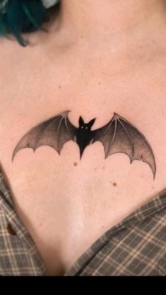 a woman's chest with a bat tattoo on it