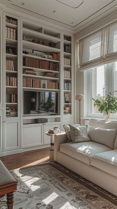 a living room filled with lots of white furniture and bookshelves next to a window