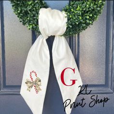 a door hanger with a candy cane wreath on it and the letter g painted on it