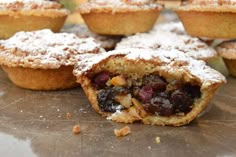 several pastries are sitting on a table with powdered sugar and cranberry toppings