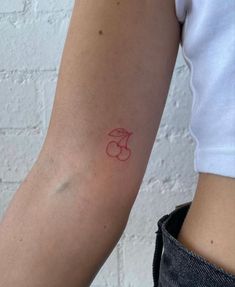 a woman's arm with a red ink tattoo on the left side of her arm