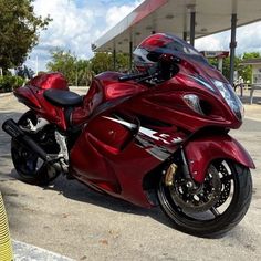 a red motorcycle parked in front of a gas station with no one on it's bike