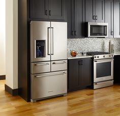 a modern kitchen with stainless steel appliances and wood flooring is pictured in this image