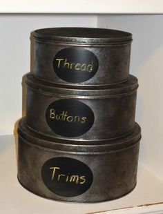 three metal containers stacked on top of each other with words written on the lids and bottom