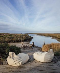 two bean bag chairs sitting on top of a wooden deck next to a body of water