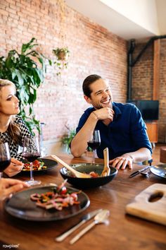 three people sitting at a table with food and wine