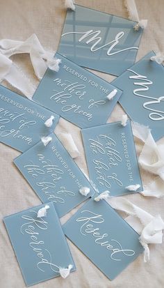 six blue wedding signs with white calligraphy on them and ribbon tied around the edges