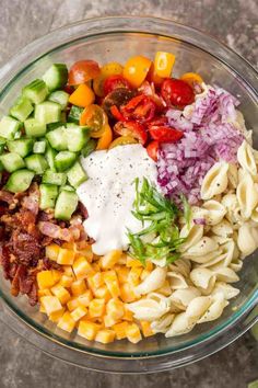 a glass bowl filled with pasta salad ingredients