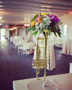 a brass trumpet with flowers in it is on display at a banquet hall or wedding reception