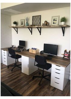 a desk with two computers on it and some shelves above the desk in an office